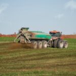 A tractor land applying biosolids on farm field